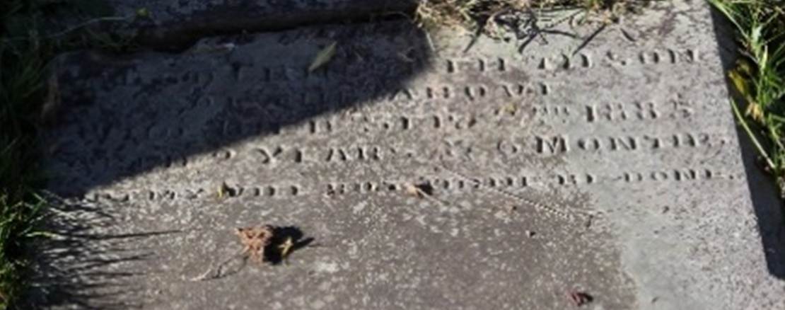 A tombstone in the grass
Description automatically generated